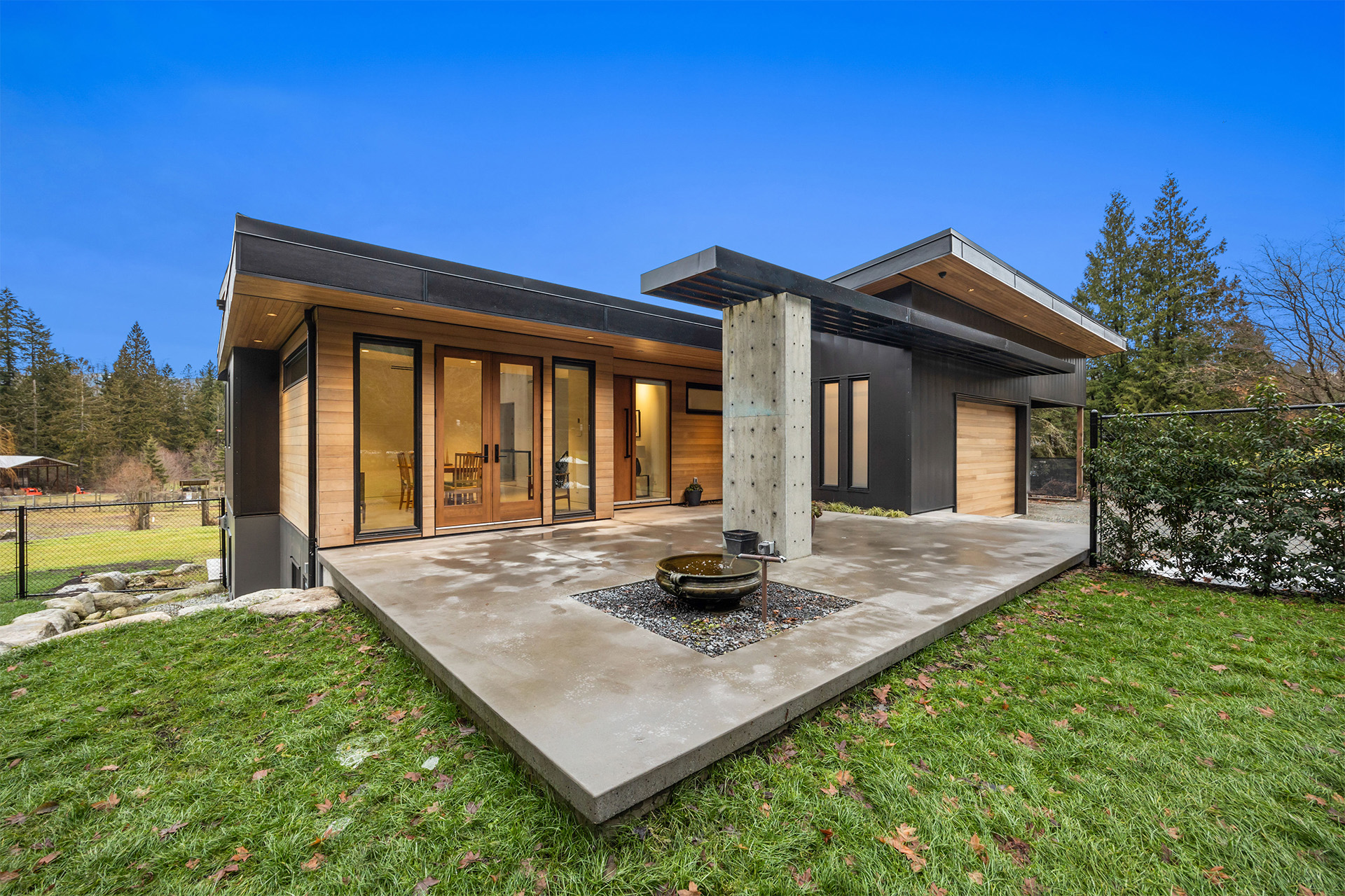 Modern contemporary home with black exterior, wood accents, and expansive glass doors in Abbotsford