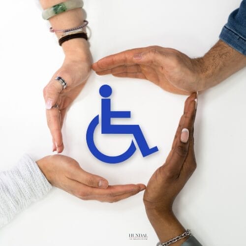 Multiple hands of different skin tones forming a circle around the blue wheelchair accessibility symbol, representing community support and inclusion at Hundal Counselling Centre in Abbotsford