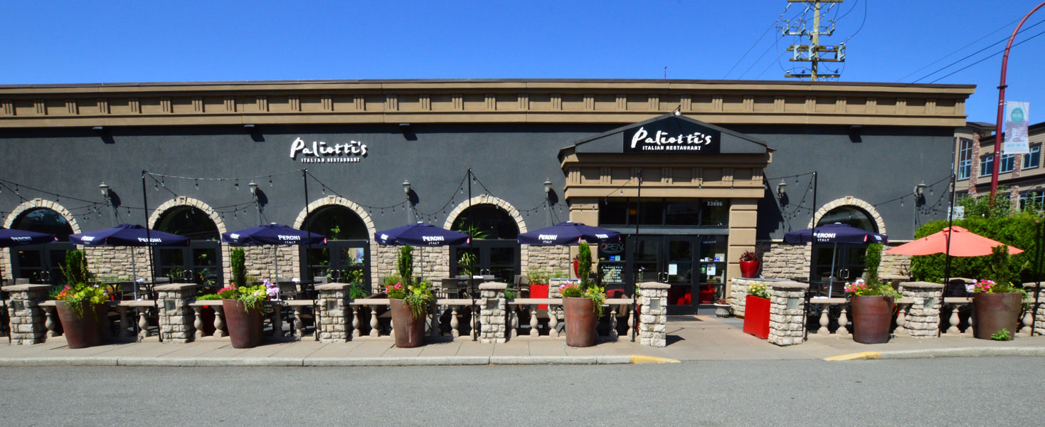 Paliotti's Italian Restaurant storefront in Abbotsford featuring arched windows, blue awnings, and outdoor patio seating