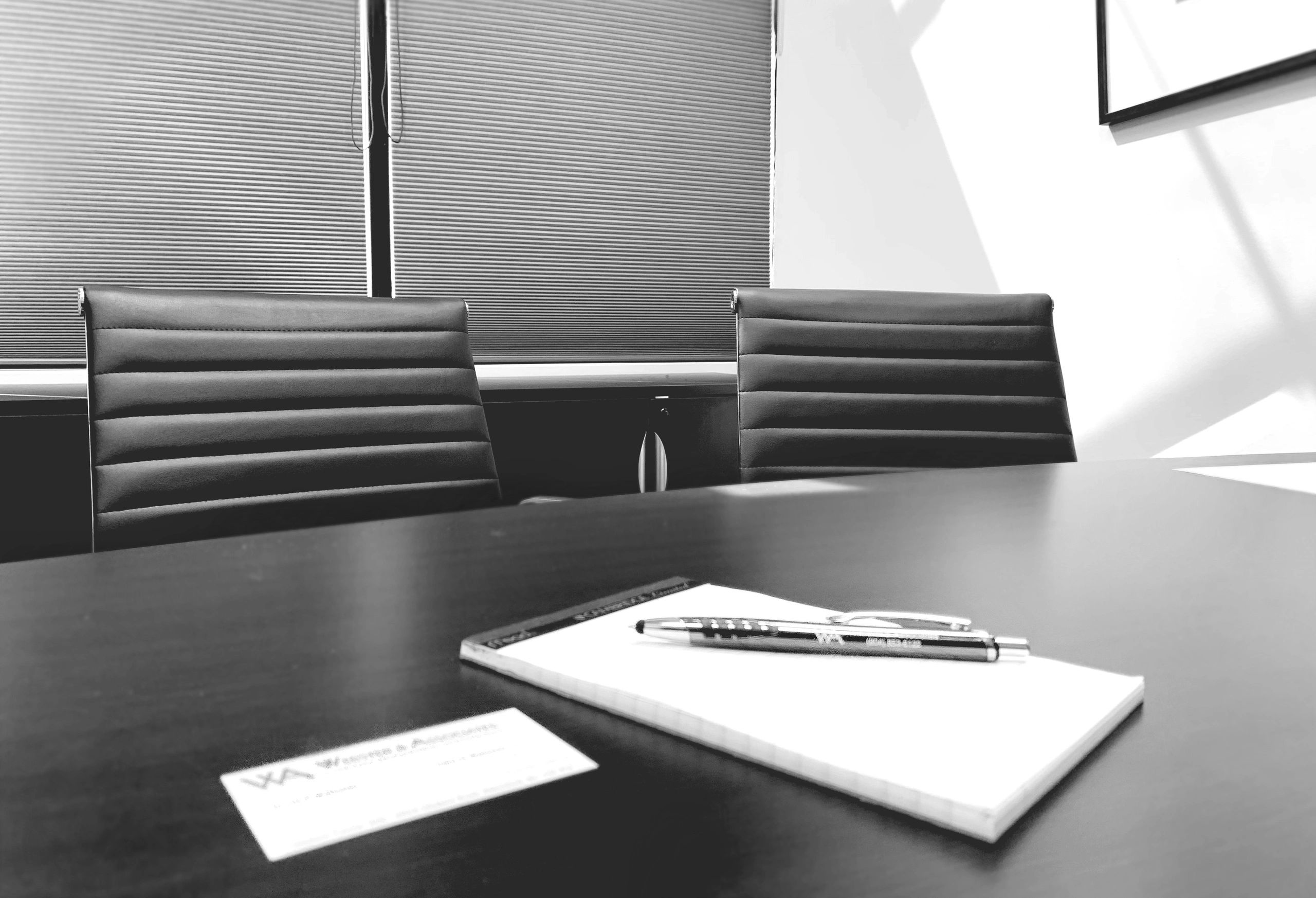 Modern black and white conference room in Abbotsford with dark table, ribbed leather chairs, notepad and pen, and horizontal window blinds