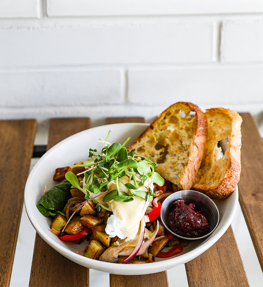 Eggs Benedict bowl served at Little Sprout Café in Abbotsford featuring toasted bread, roasted potatoes, fresh greens, poached egg, and a side of hollandaise sauce