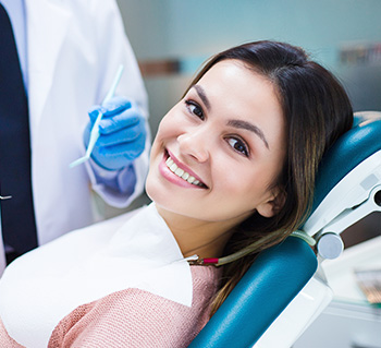 Happy female dental patient in blue chair at Abbotsford dental office smiling during examination
