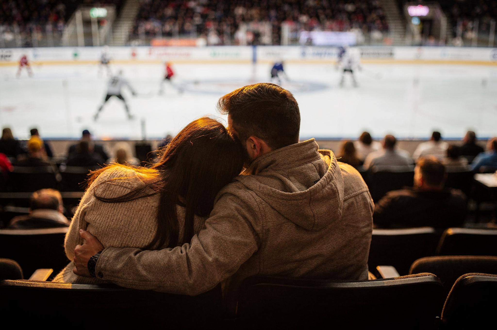 couple watching a hockey game together from the stands, viewed from behind | GPS: 49.145898, -122.523642