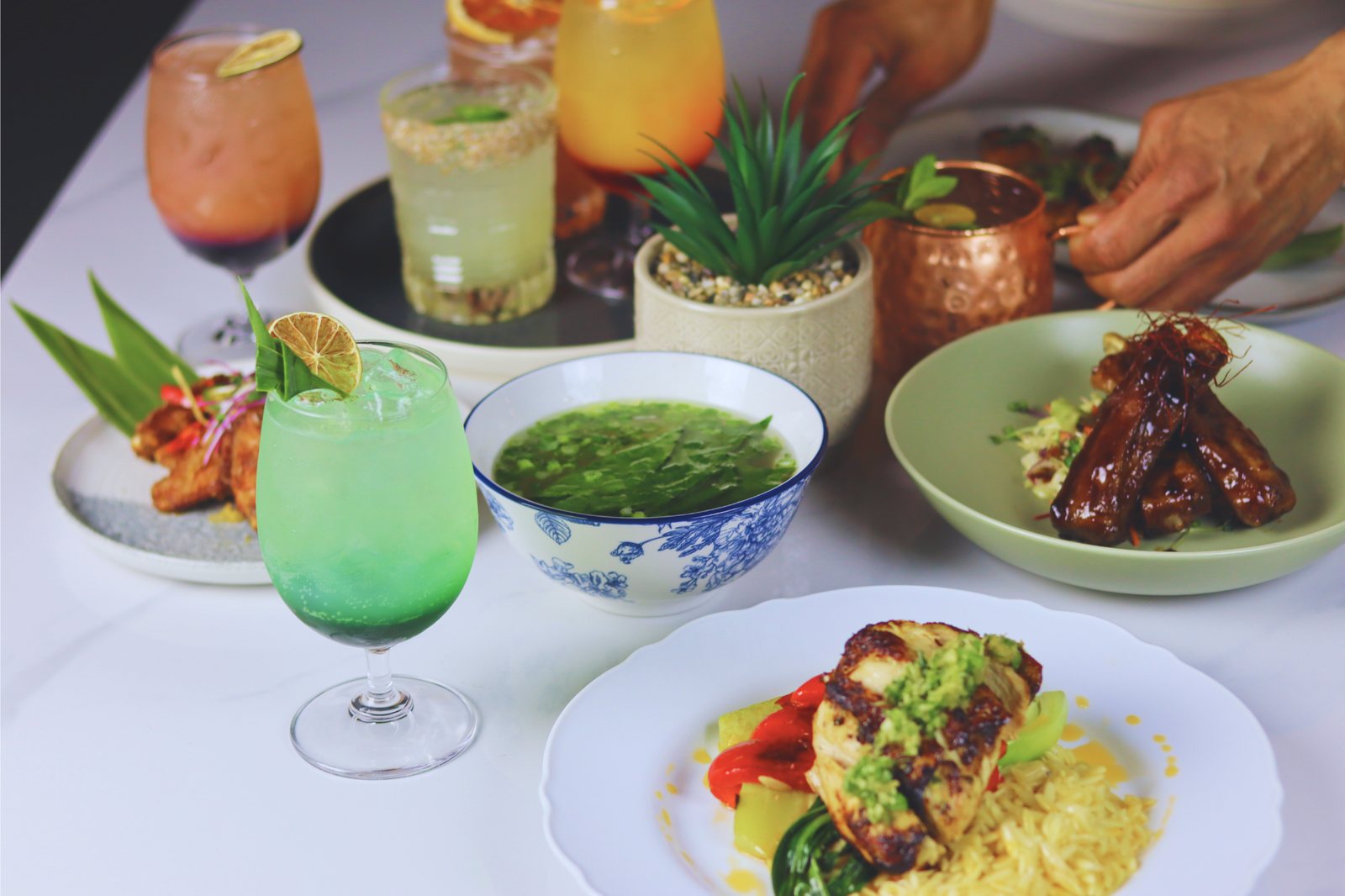 Halina cocktails and shared Filipino plates on a white table